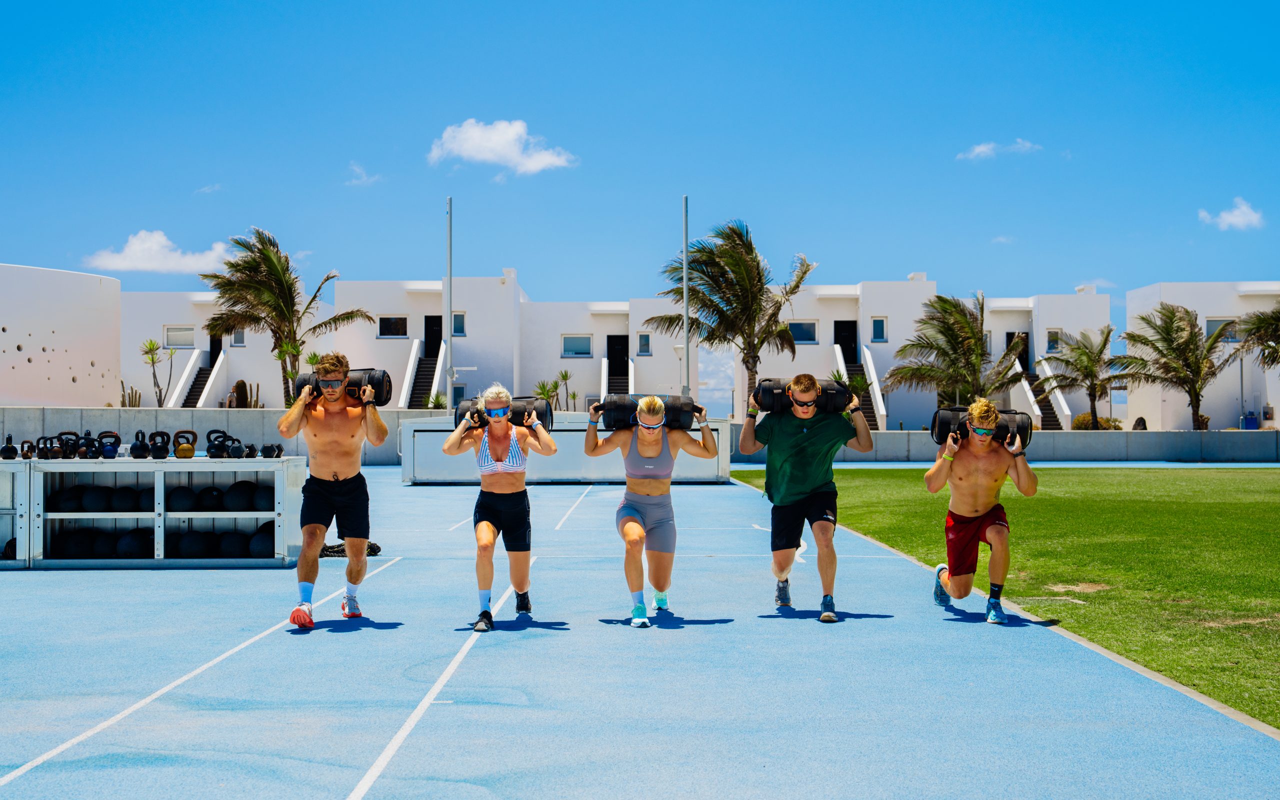 People doing weighted lunges on the running track in a functional training class
