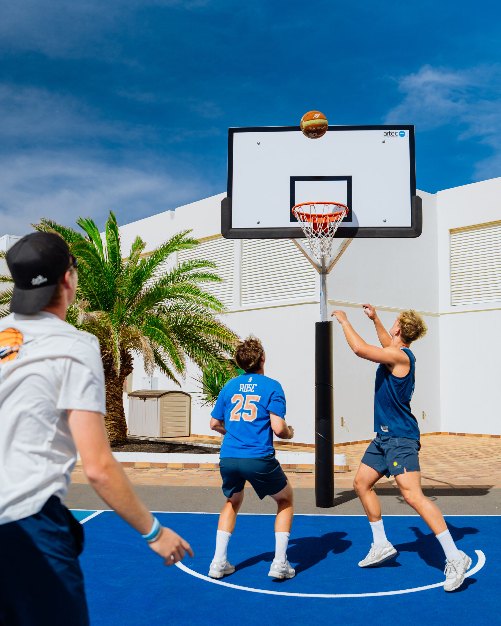 A group of males playing basketball on the outdoor court at Club La Santa