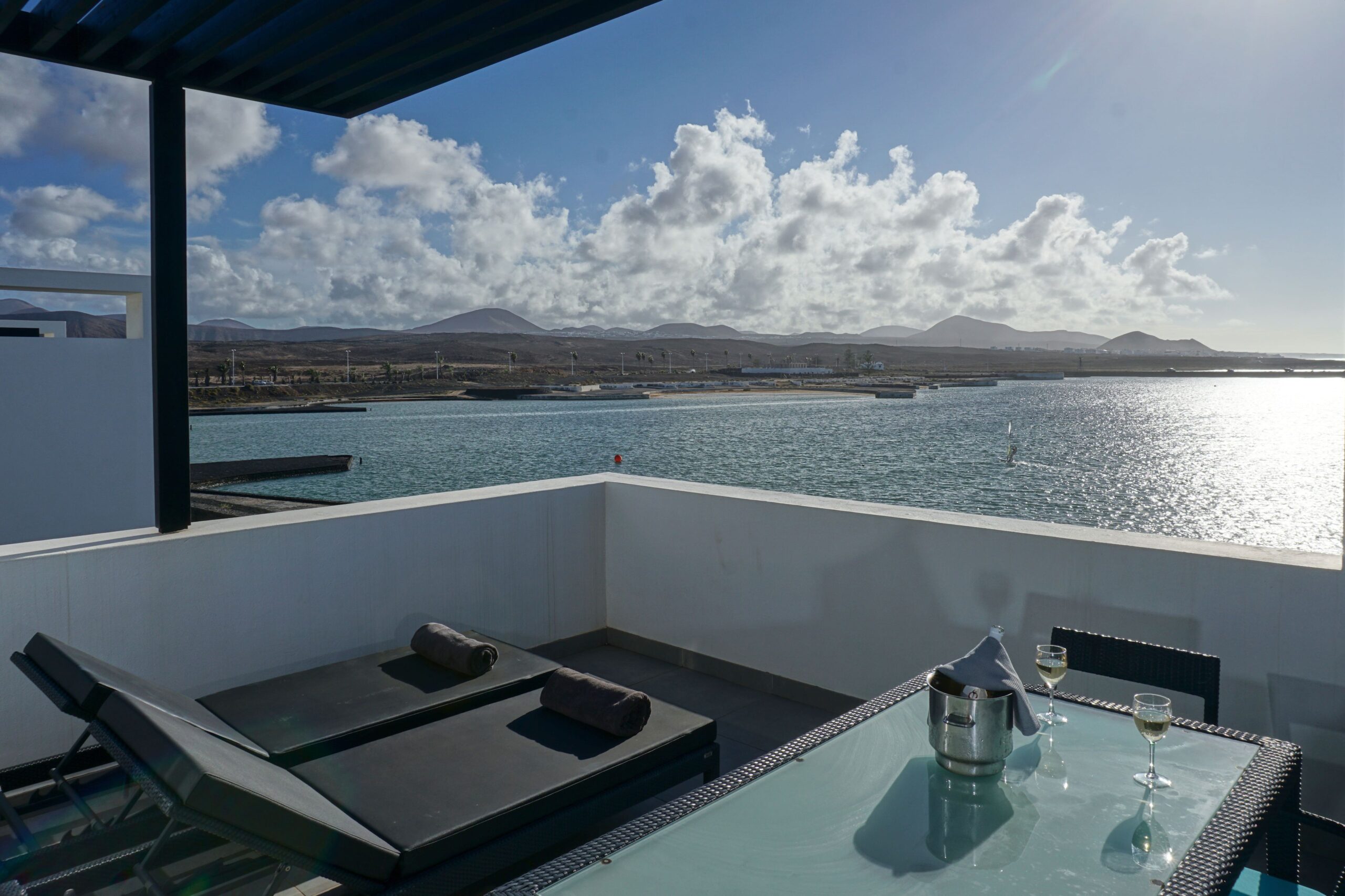 2 sunloungers and a dining table on the terrace of a suite with a sea view.