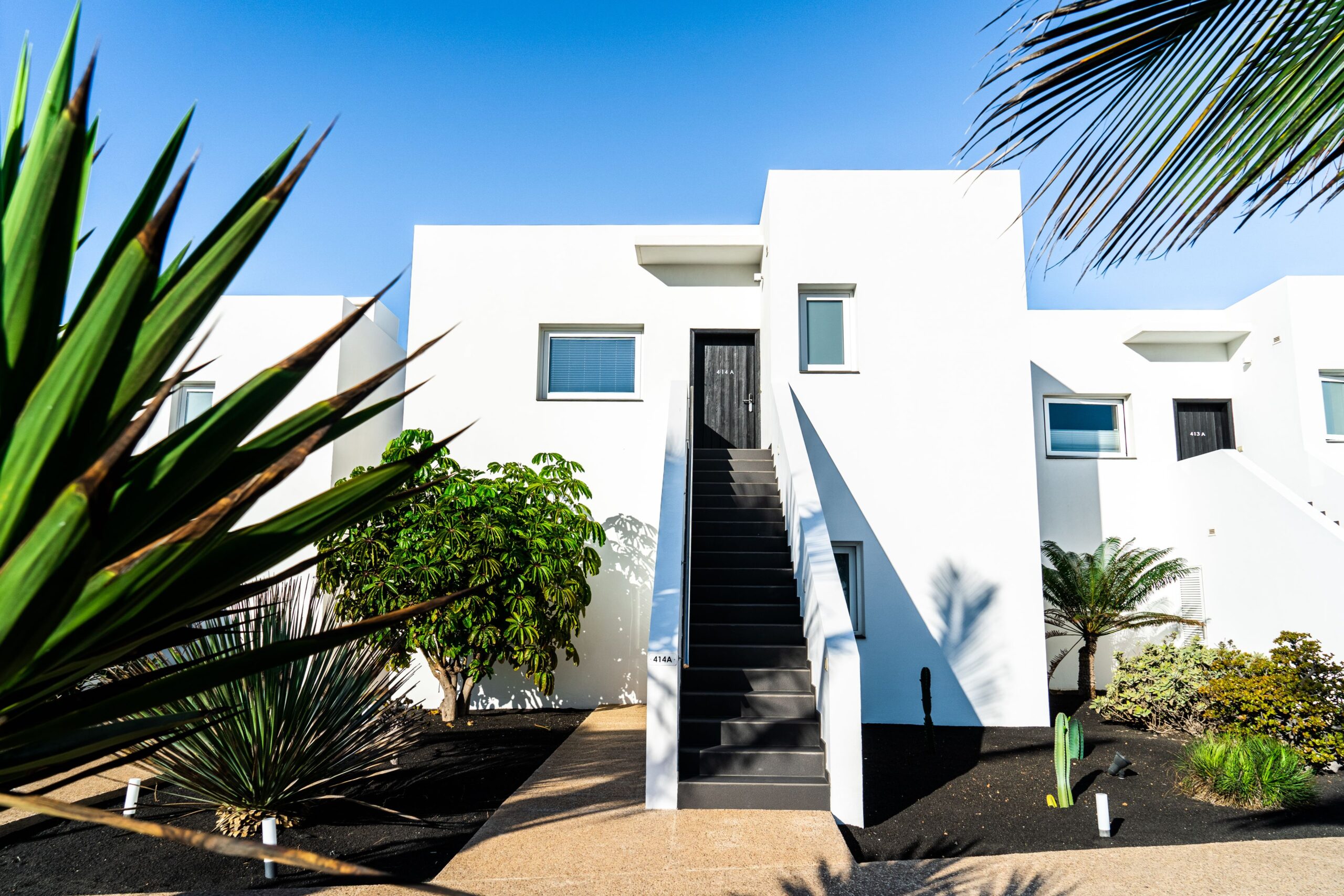 The outside of a suite, with white exterior walls and a black staircase leading up to the front door