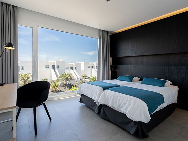 A spacious bedroom, with 2 single beds and a workspace with a desk and office chair