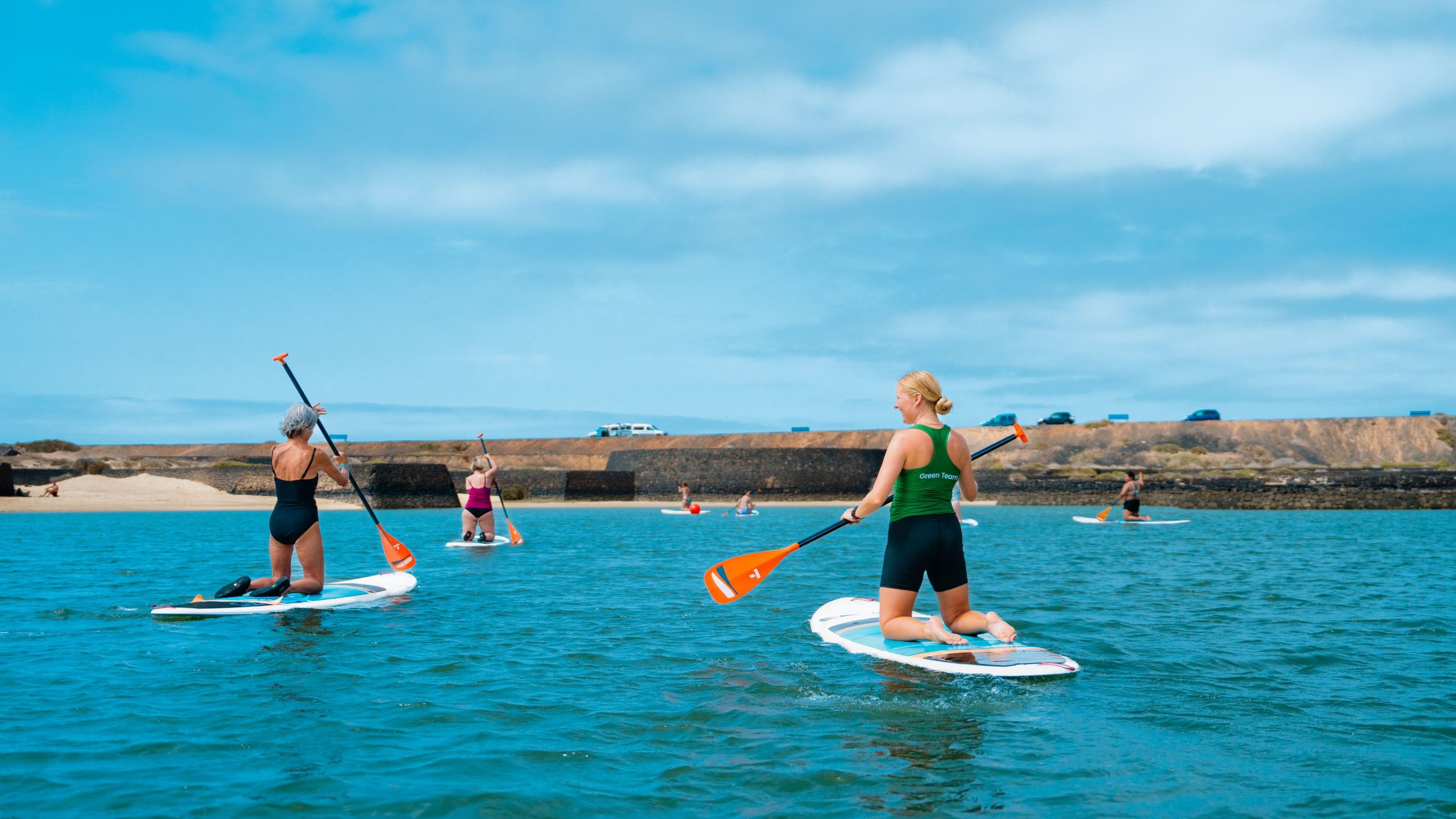 A group kneeling  on the stand up paddle boards on their watersports holiday to Club La Santa