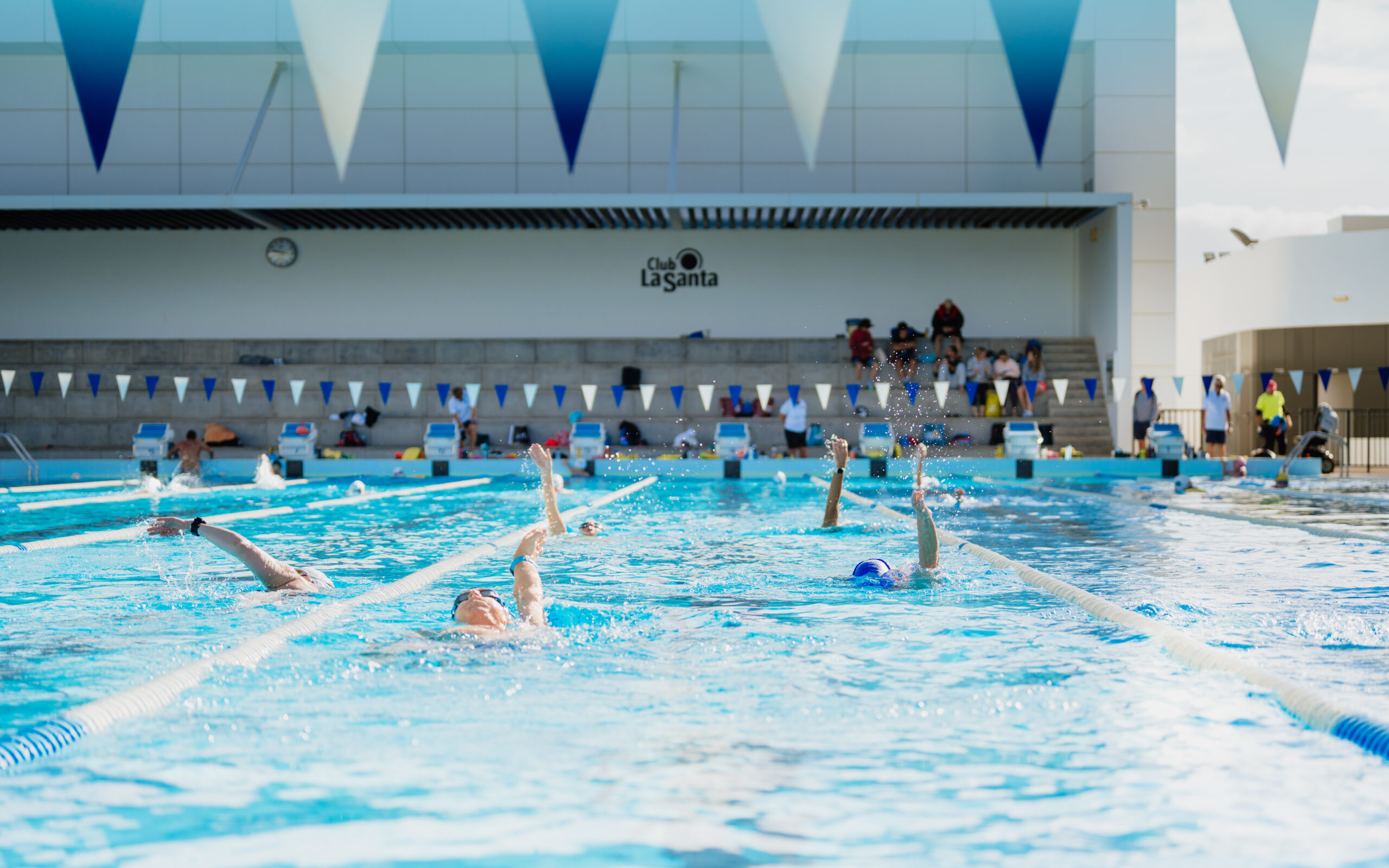 People attending a swimming camp at Club La Santa, swimming back-stroke in the 50m pool.