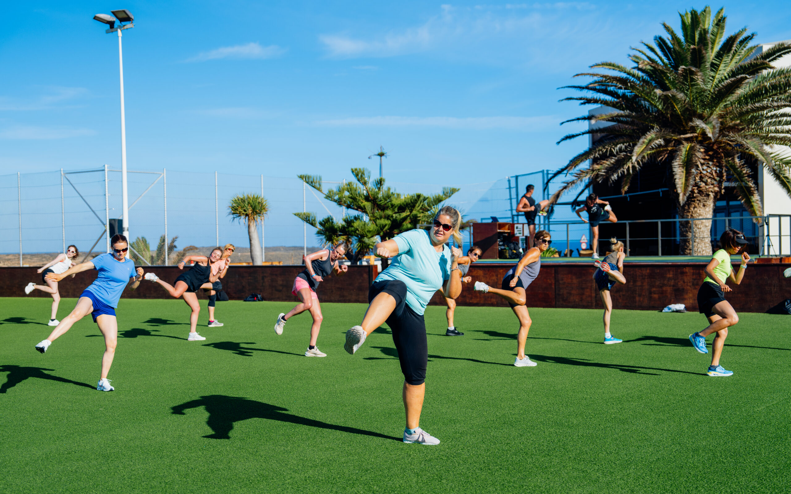 A group of people kicking the air in a full body workout class at Club La Santa, Lanzarote.