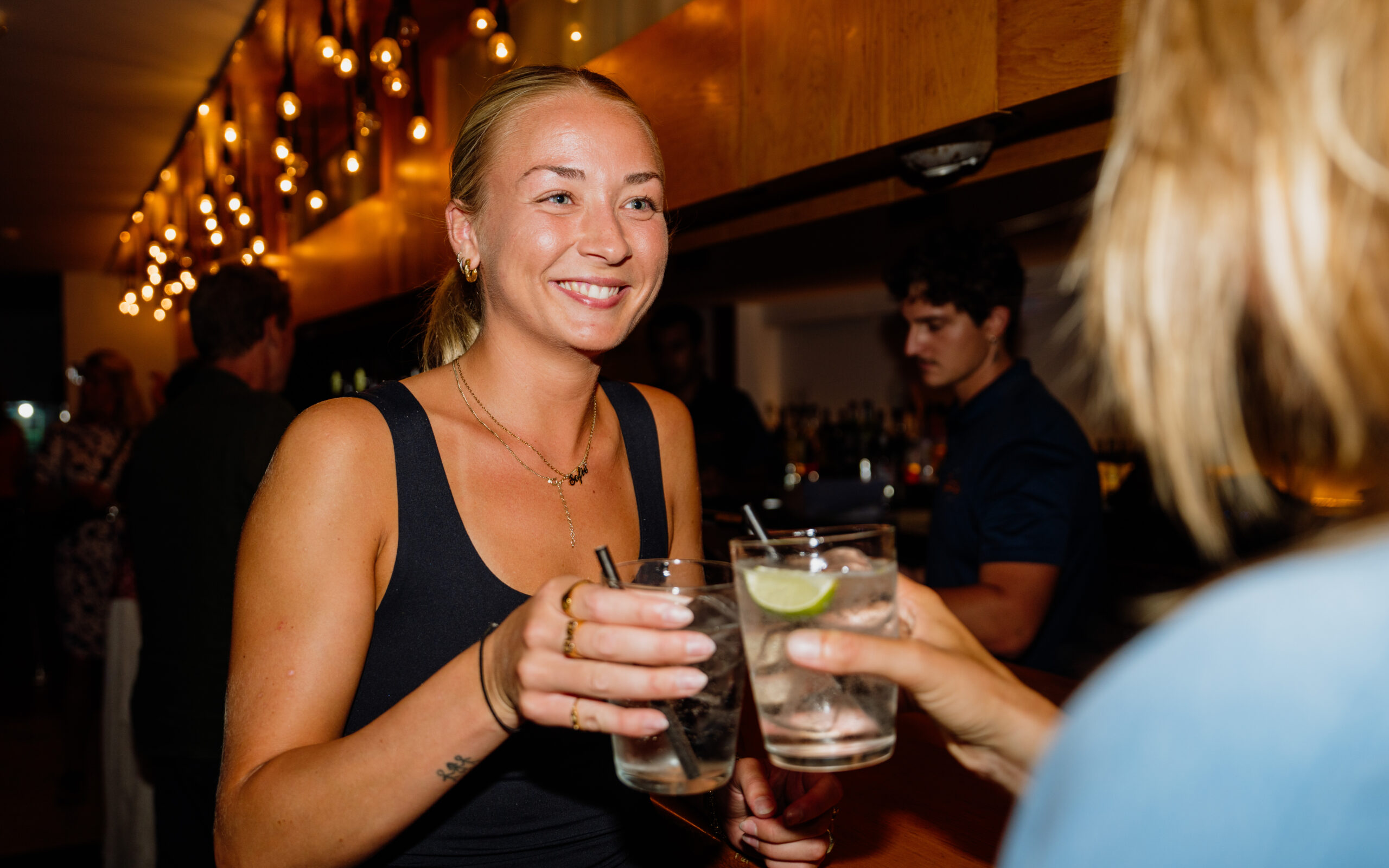 2 female guests at Club La Santa, clinking their glasses together in the bar during evening entertainment at Club La Santa.