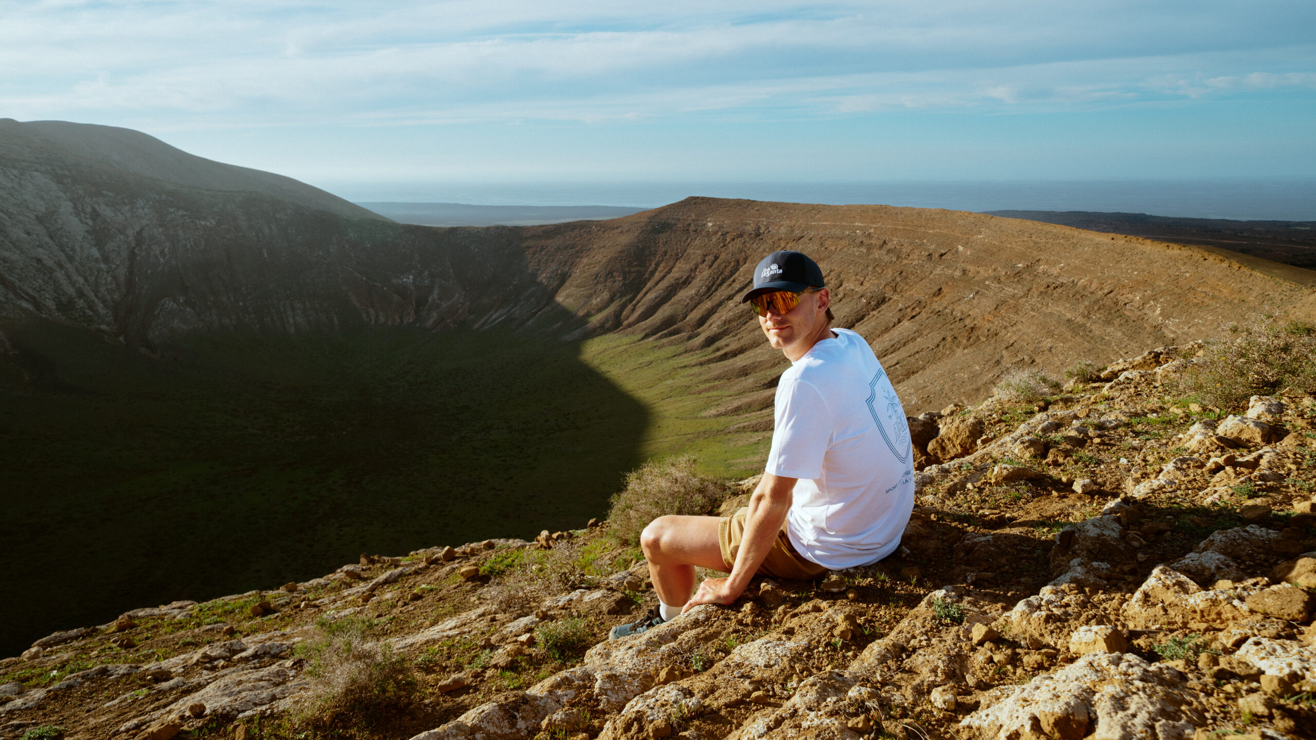 A man sat on top of a volcano, with a tremendous view of the mountains or an excursion from Club La Santa.