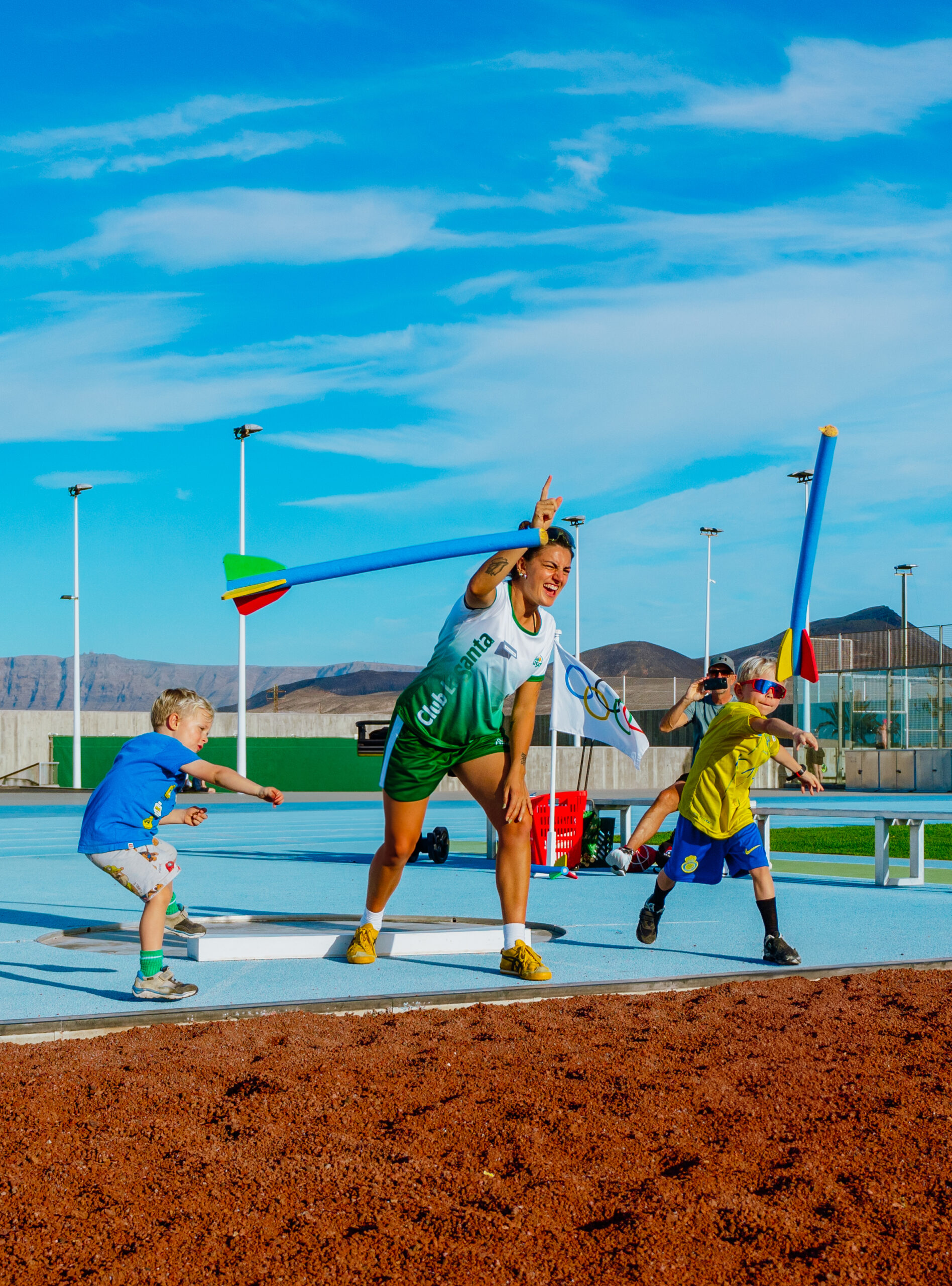 A member of the Green Team throwing foam javelins with two young boys at Club La Santa.