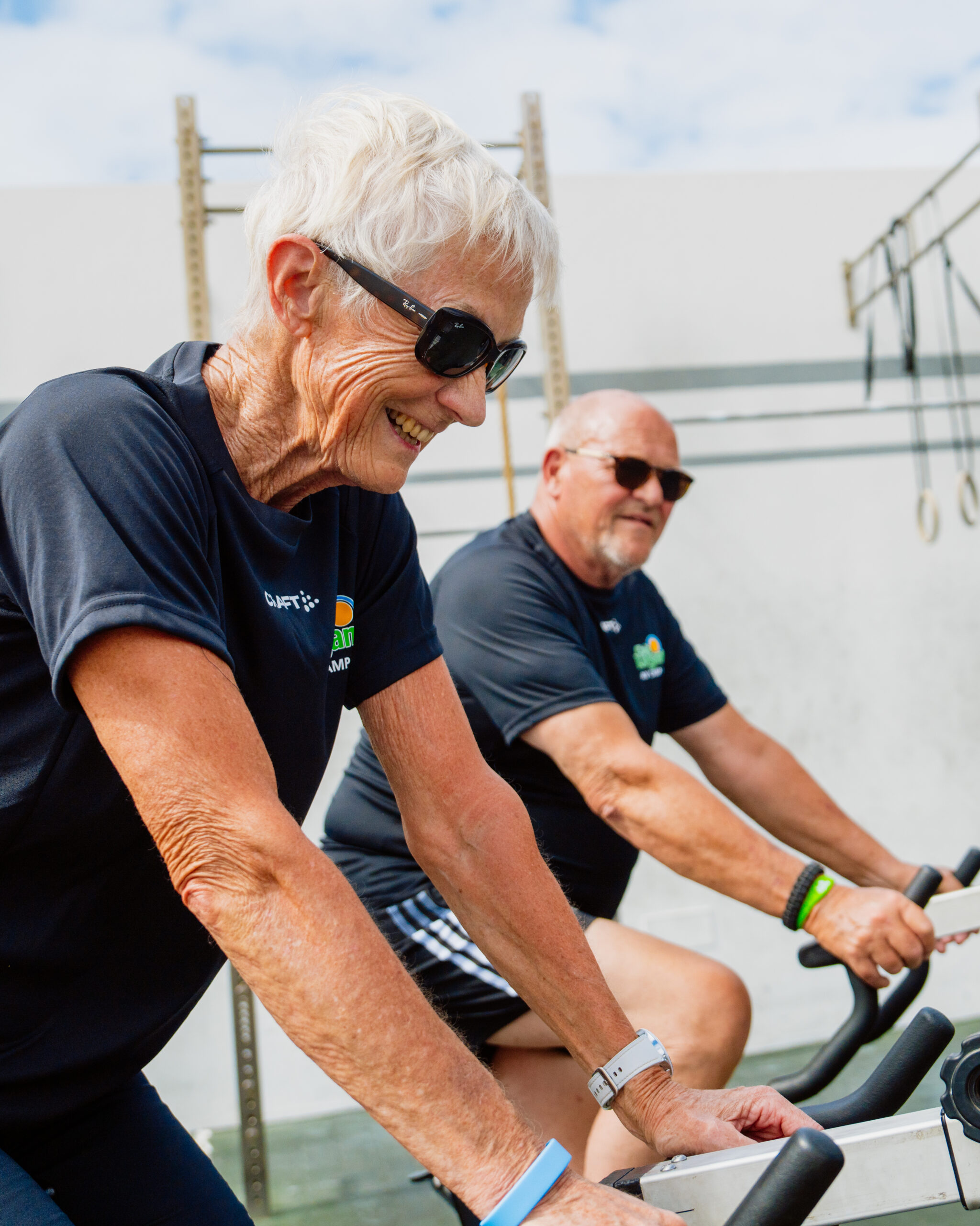 This image shows two individuals engaged in a workout session on stationary bikes.