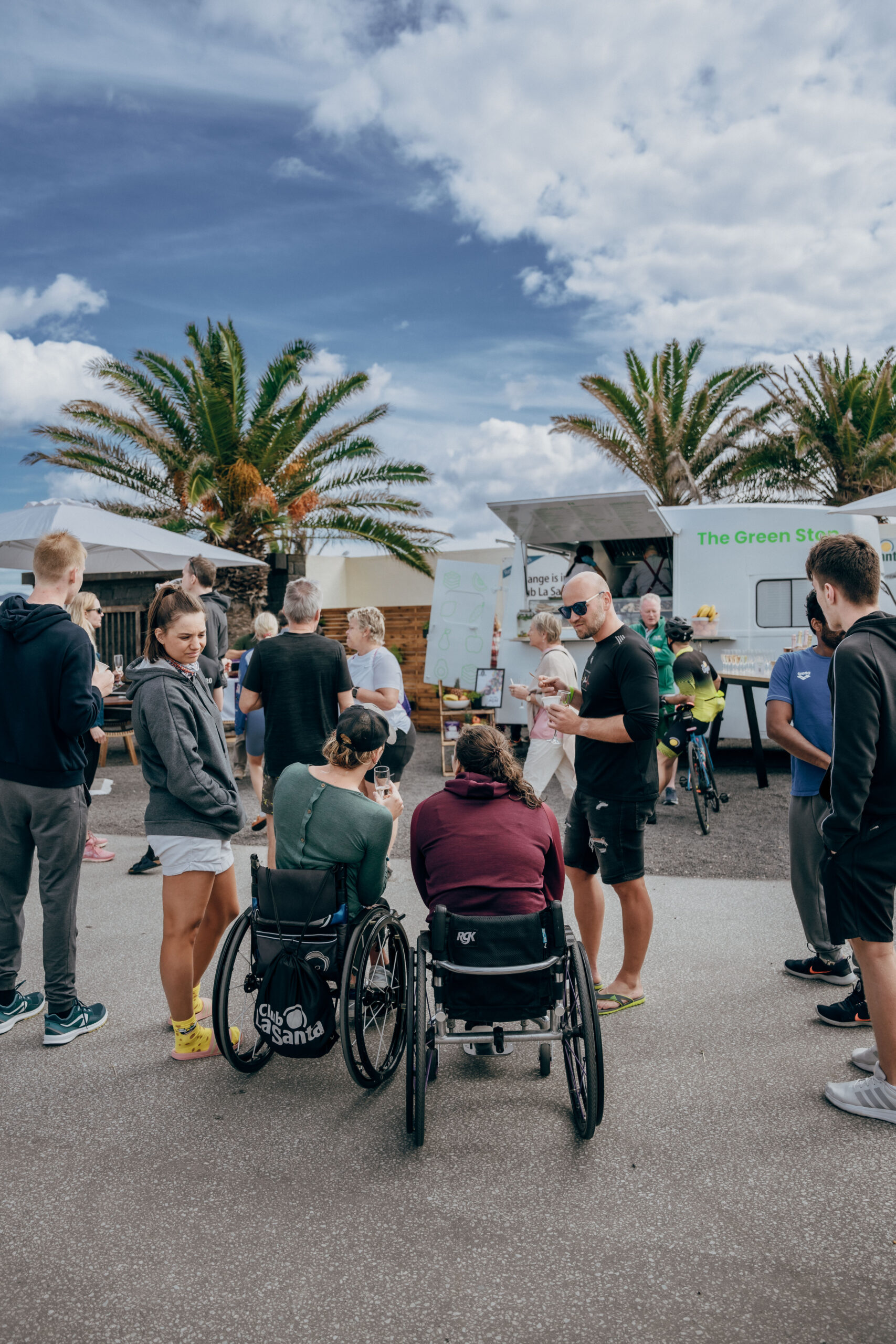 a group of people stood next to a food truck at Club La Santa. 2 members of the group are in wheel chairs.