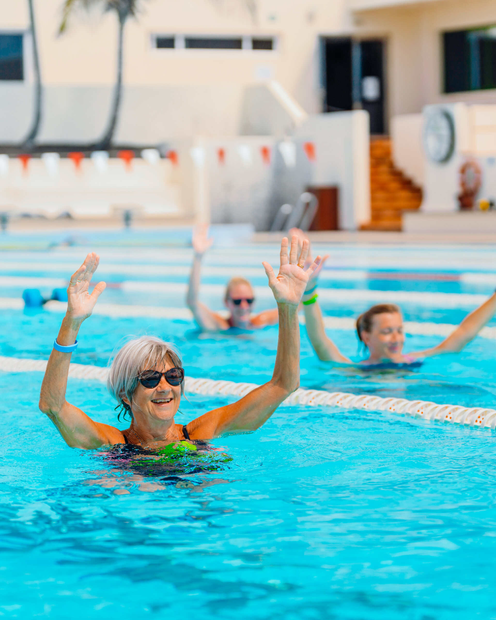 People in the swimming pool with their arms up in the air, during an aqua fitness class.